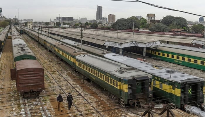 Policemen walk along trains stationed on deserted platform at Karachi Cantonment railway station. — AFP