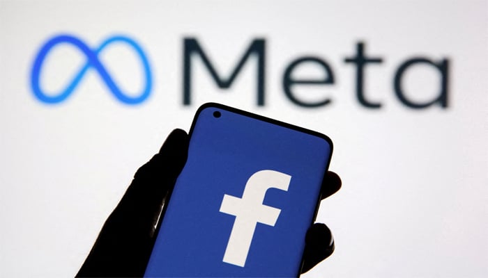 A smartphone with Facebooks logo is seen in front of the displayed Facebooks new rebranded logo, Meta, is in this illustration taken on October 28, 2021. — Reuters