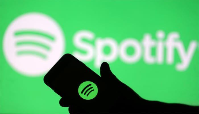 A smartphone is seen in front of a screen projection of Spotify logo, in this picture illustration taken April 1, 2018. — Reuters