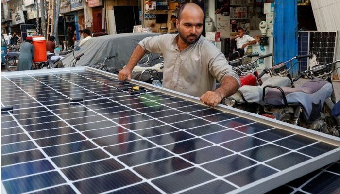 An image of a worker loading solar panels on a vehicle, outside a shop at a market selling electronic items in Karachi, Pakistan June 11, 2024. — Reuters