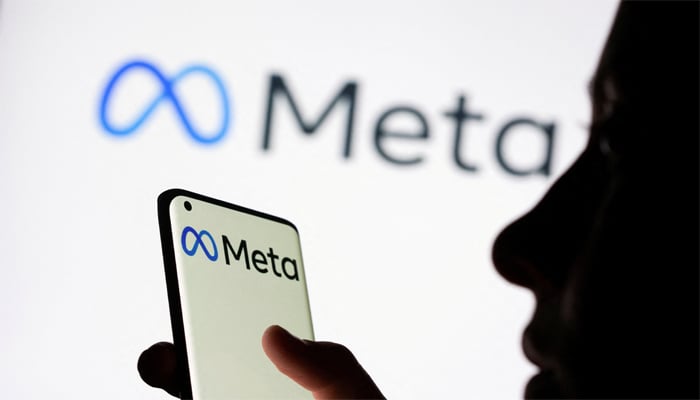 Woman holds smartphone with Meta logo in front of a displayed Facebooks new rebrand logo Meta in this illustration picture taken October 28, 2021. — Reuters