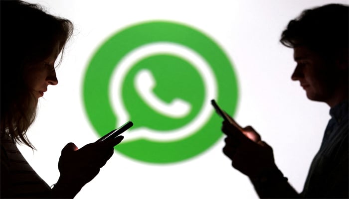 Teenagers pose for a photo while holding smartphones in front of a Whatsapp logo in this illustration taken September 11, 2025. — Reuters