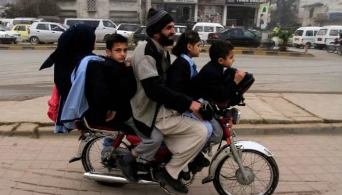 Children ride on a motorcycle with their parent in Rawalpindi. — Reuters/file
