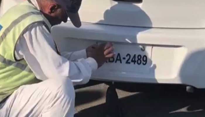 An undated image shows traffic police constable removes fancy number plate from a car in Karachi. — X/@Khitrafficpol