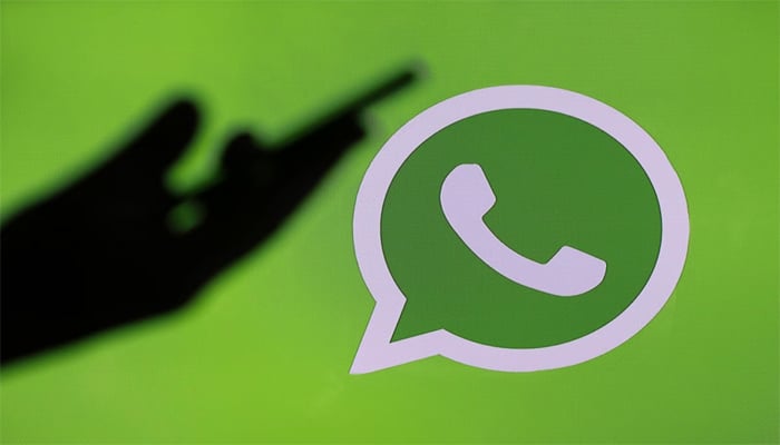 An undated image shows silhouette of mobile in persons hand along with WhatsApp logo. — Getty Images