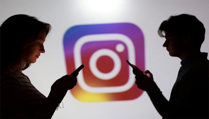 Teenagers pose for a photo while holding smartphones in front of a Instagram logo in this illustration taken September 11, 2025. — Reuters