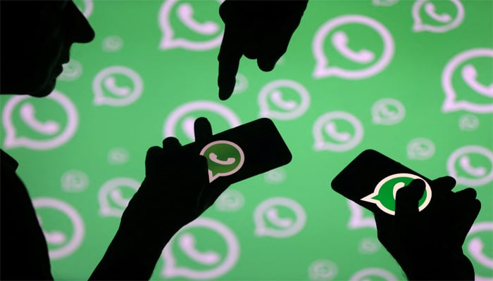 Men pose with smartphones in front of displayed WhatsApp logo in this illustration September 14, 2017. — Reuters