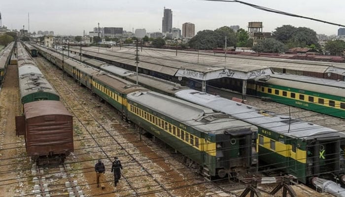 An undated image shows policemen walk along trains stationed on a deserted platform at Karachi Cantonment railway station. — AFP