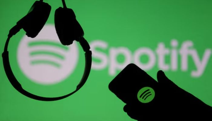 A smartphone and a headset are seen in front of a screen projection of the Spotify logo in this picture illustration taken April 1, 2018. — Reuters