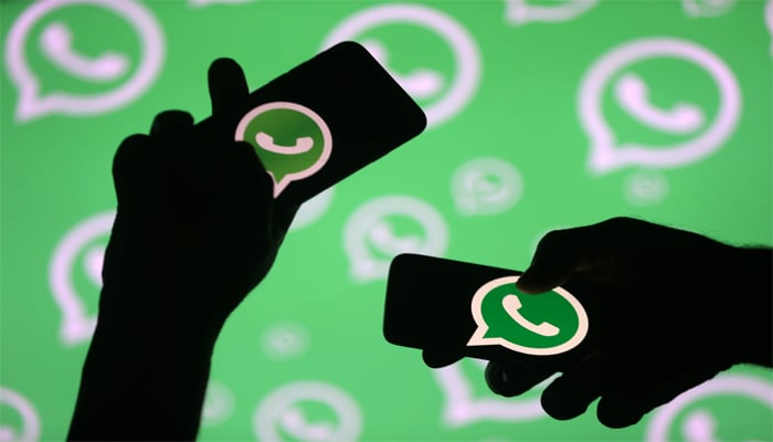 Men pose with smartphones in front of displayed WhatsApp logo in this illustration September 14, 2017. — Reuters