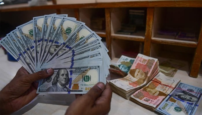 A foreign currency dealer counts US dollars at shop in Karachi on May 19, 2025. — AFP