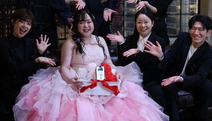 An image of Yurina Noguchi, 32, holding her smartphone showing an AI-generated image of her partner during a ceremonial wedding in Okayama, Japan, October 27, 2025. — Reuters