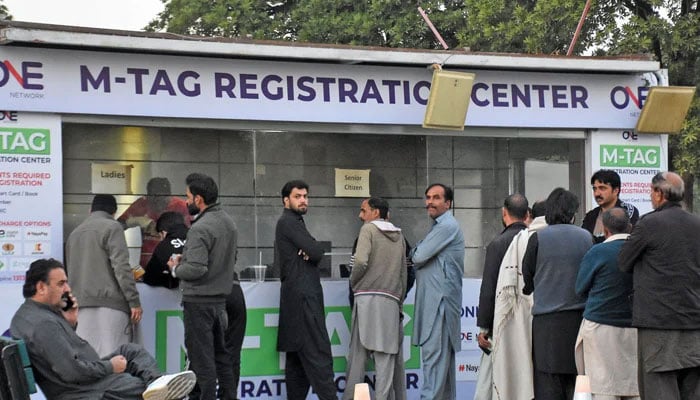 This undated image shows people standing in a queue for M-tag registration. — Online