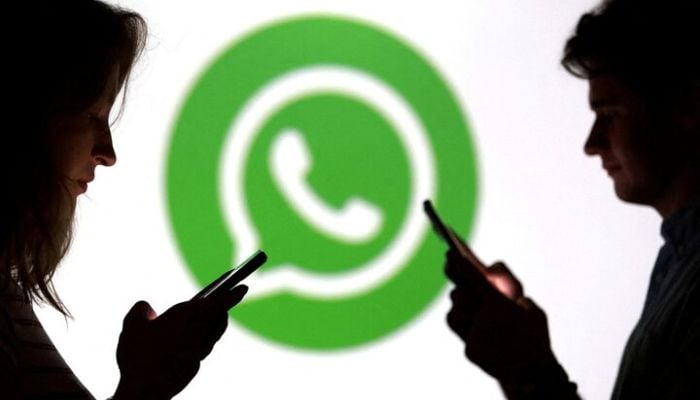 Teenagers pose for a photo while holding smartphones in front of a Whatsapp logo in this illustration taken September 11, 2025. — Reuters