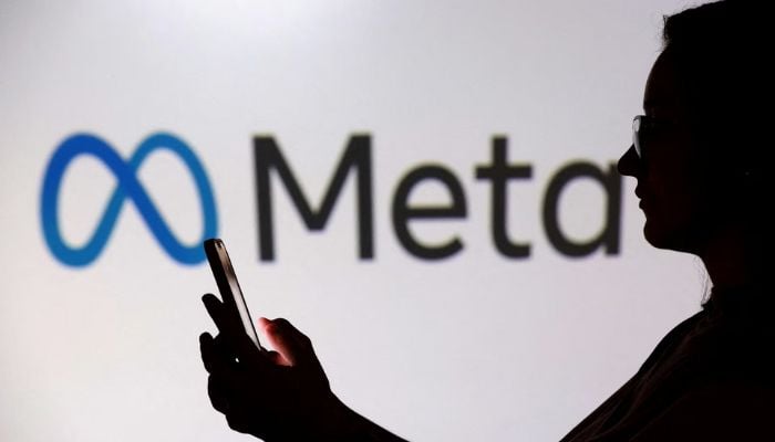 A teenager poses for a photo while holding a smartphone in front of a Meta logo in this illustration taken September 11, 2025. — Reuters