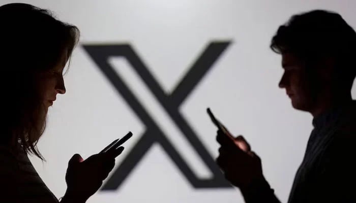 Teenagers pose for a photo while holding smartphones in front of a X logo in this illustration taken September 11, 2025. — Reuters