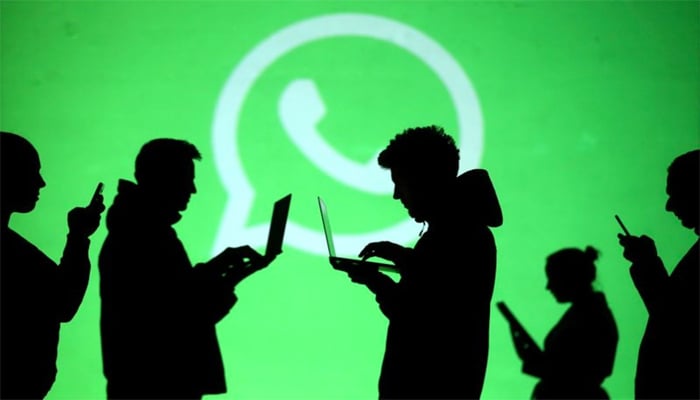 Silhouettes of laptop and mobile device users are seen next to a screen projection of Whatsapp logo in this picture illustration taken March 28, 2018. — Reuters