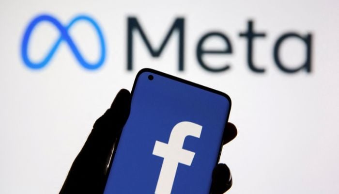 A smartphone with Facebooks logo is seen in front of displayed Facebooks new rebrand logo Meta in this illustration taken October 28, 2021. — Reuters