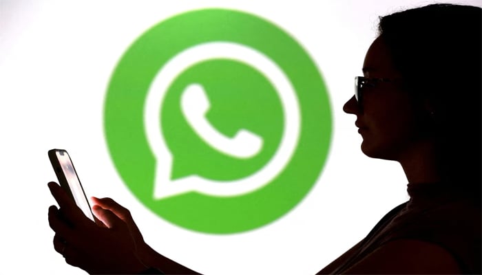 A teenager poses for a photo while holding a smartphone in front of a Whatsapp logo in this illustration taken September 11, 2025. — Reuters