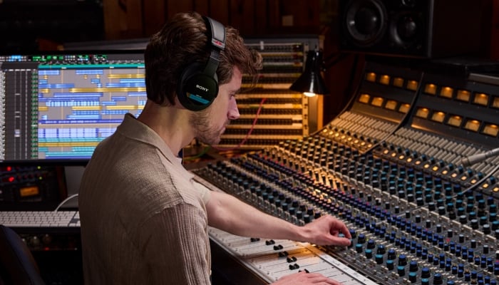 An undated image shows a person using Sony MDR-M1 Headphones, while working on a musical device. — Sony Electronics