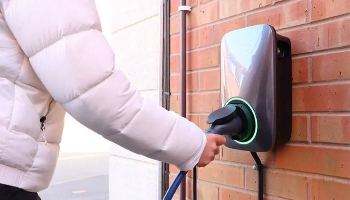 An undated image of a person using an EV charger. — ProjectEV