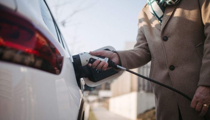 An undated image of a man holding an EV charger. — QMerit