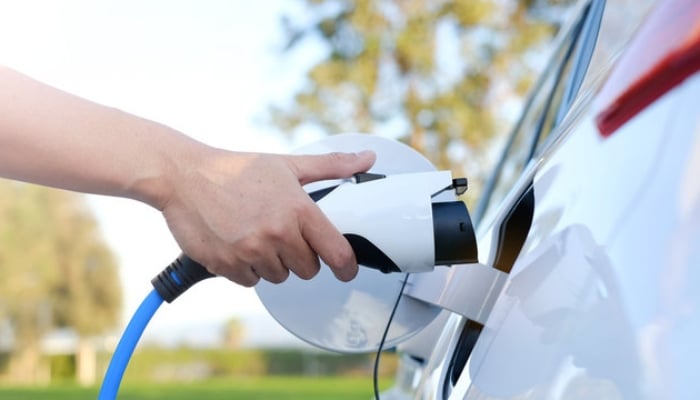 An undated image shows a person charging his electric vehicle (EV). — Adobe Stock