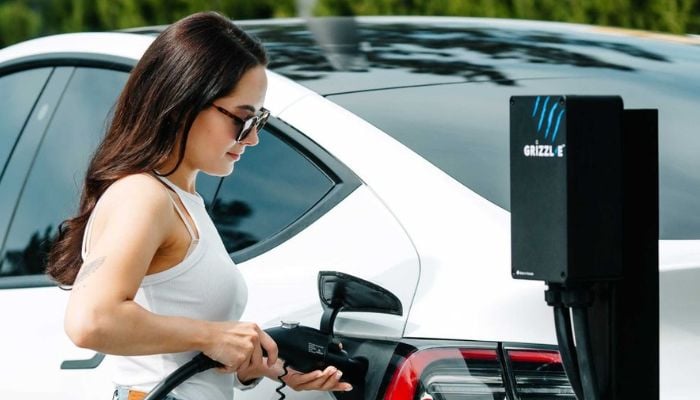 An undated image of a woman using an EV charger. — Grizzl-E
