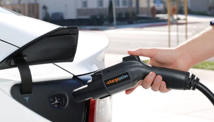 An undated image shows an EV being charged using a ChargePoint charging connector at a residential location.