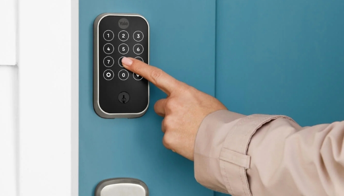 An undated image shows a person inputting passkey to unlock door. — Yale